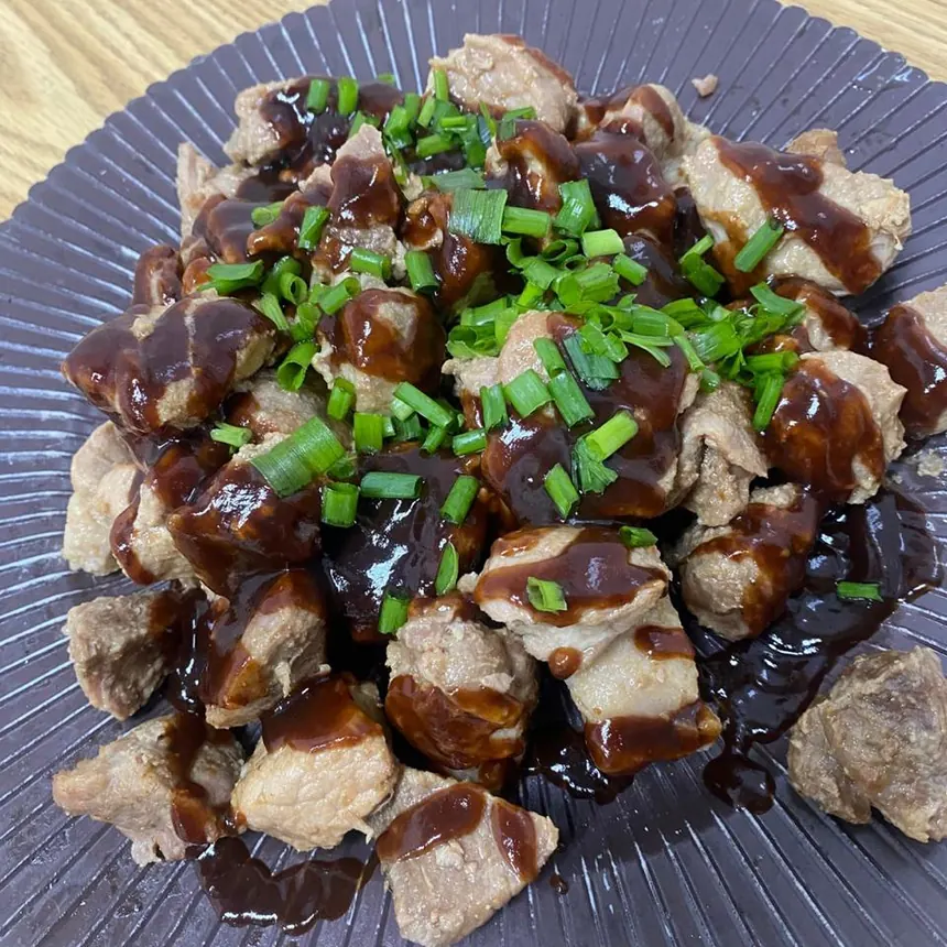 Cubos de carne ao molho escuro finalizados com cebolinha