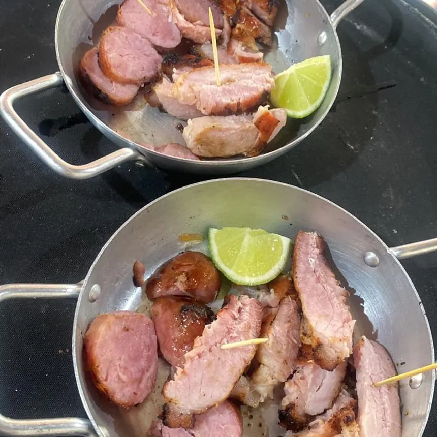 Linguiça e carne grelhadas servidas em panelinhas com limão