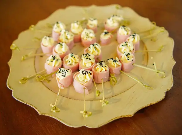 Doces em tons de rosa e dourado servidos em prato de festa