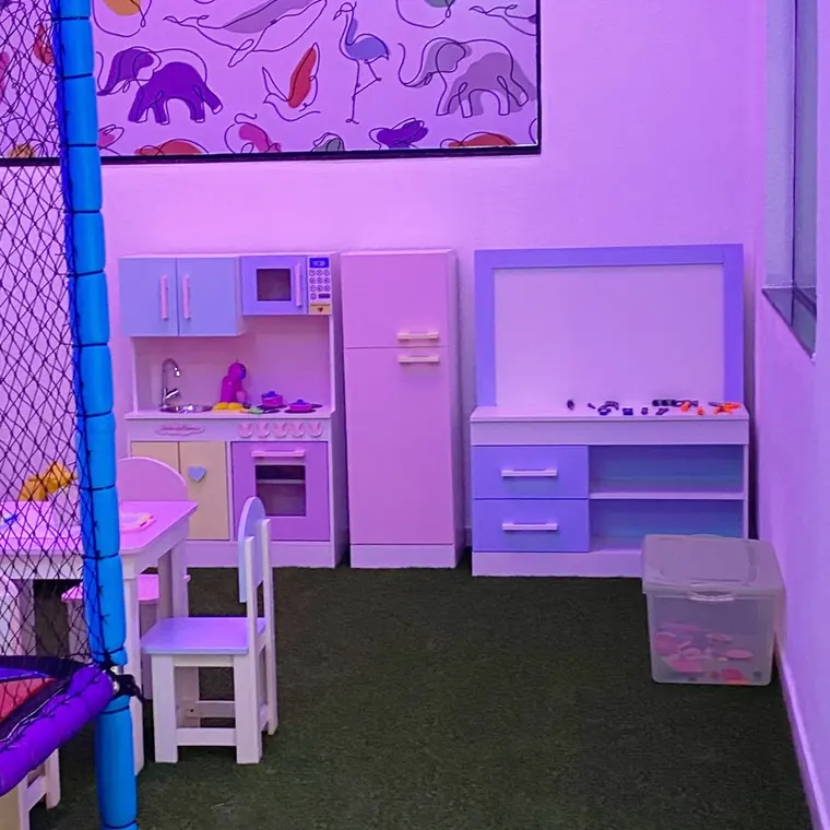 Sala de brinquedos com cozinha de brinquedo e mural colorido na parede